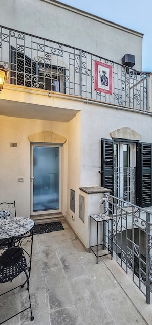 A building with a balcony, a door, and a table with chairs. - Monte Bello Suites (Montescaglioso)