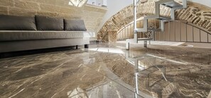 Un interior moderno con un sofá, piso de mármol pulido y pared de piedra.