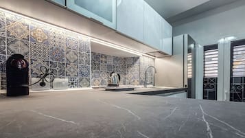 Cozinha moderna com azulejos estampados, máquina de café e pia.