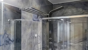 Ein modernes Badezimmer mit einer Duschkabine aus Glas, einer weißen Toilette und einem Marmor-Waschtisch.