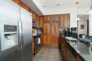 A modern kitchen with wooden cabinets, stainless steel appliances, and a built-in oven. - Stylish, fully equipped 2-bed / 2-bath condo in Riverstone Village, Coeur d'Alene, with open floor plan, fully equipped kitchen, and secure garage parking. Walkable to nearby dining, shopping, trails, parks and the waterfront. (Coeur d'Alene)