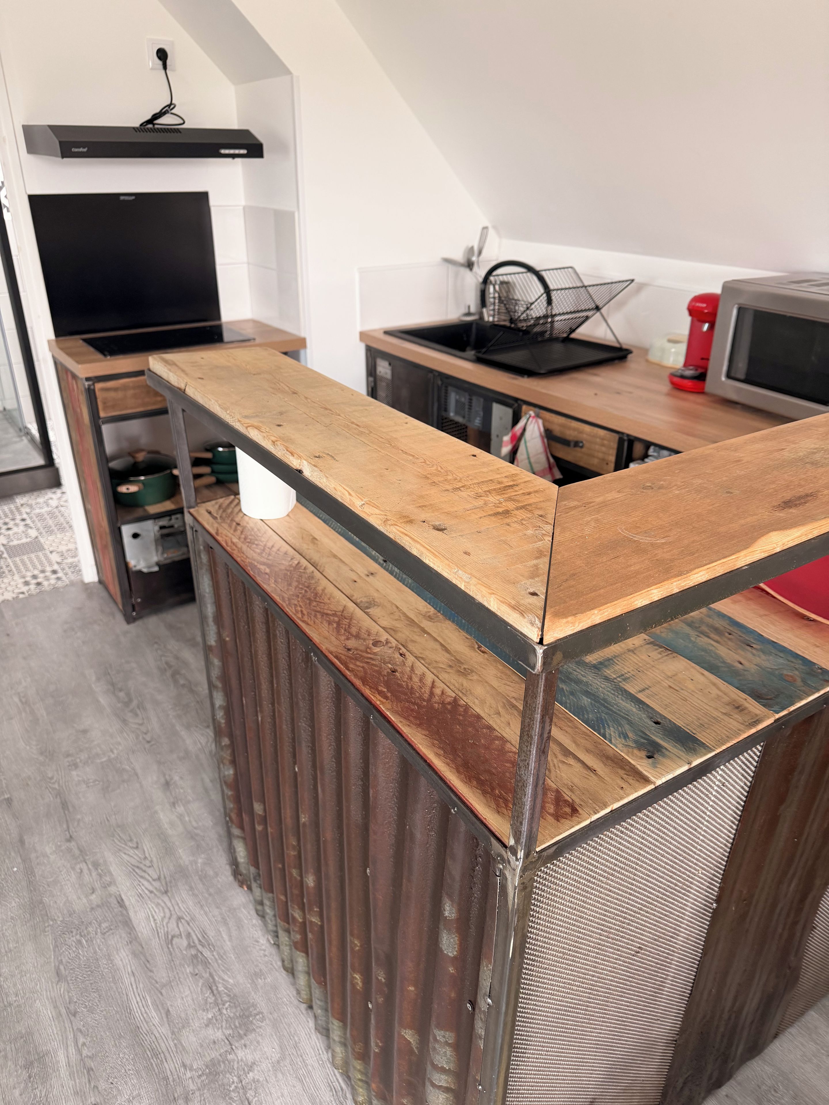 Eine Küche mit einer Holz Arbeitsplatte, einer schwarzen Dunstabzugshaube und einer Mikrowelle.