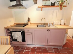 A compact kitchen with a sink, stove, and a small oven. - Felin Bach (Pwllheli)