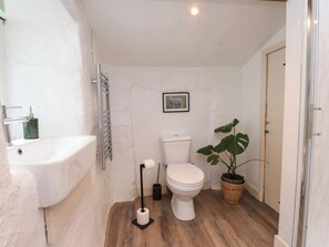 Ein kleines Badezimmer mit einem weißen Waschbecken, einer Toilette und einer großen Topfpflanze.