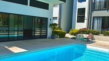 A modern building with a swimming pool, large windows, and a balcony.
