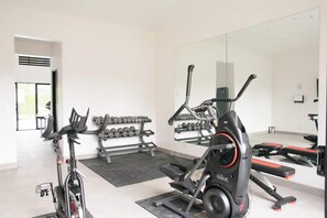 Ein modernes Fitnessstudio mit Cardiogeräten, Kurzhanteln und einer Spiegelwand.