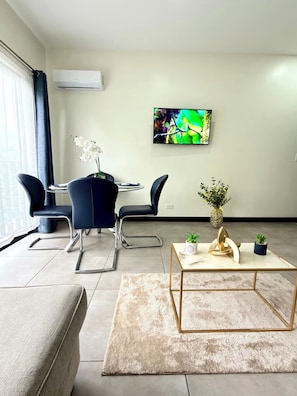A modern living room with a sofa, a coffee table, and a TV mounted on the wall. - Best place near the airport SJO with Air Cond (Alajuela)