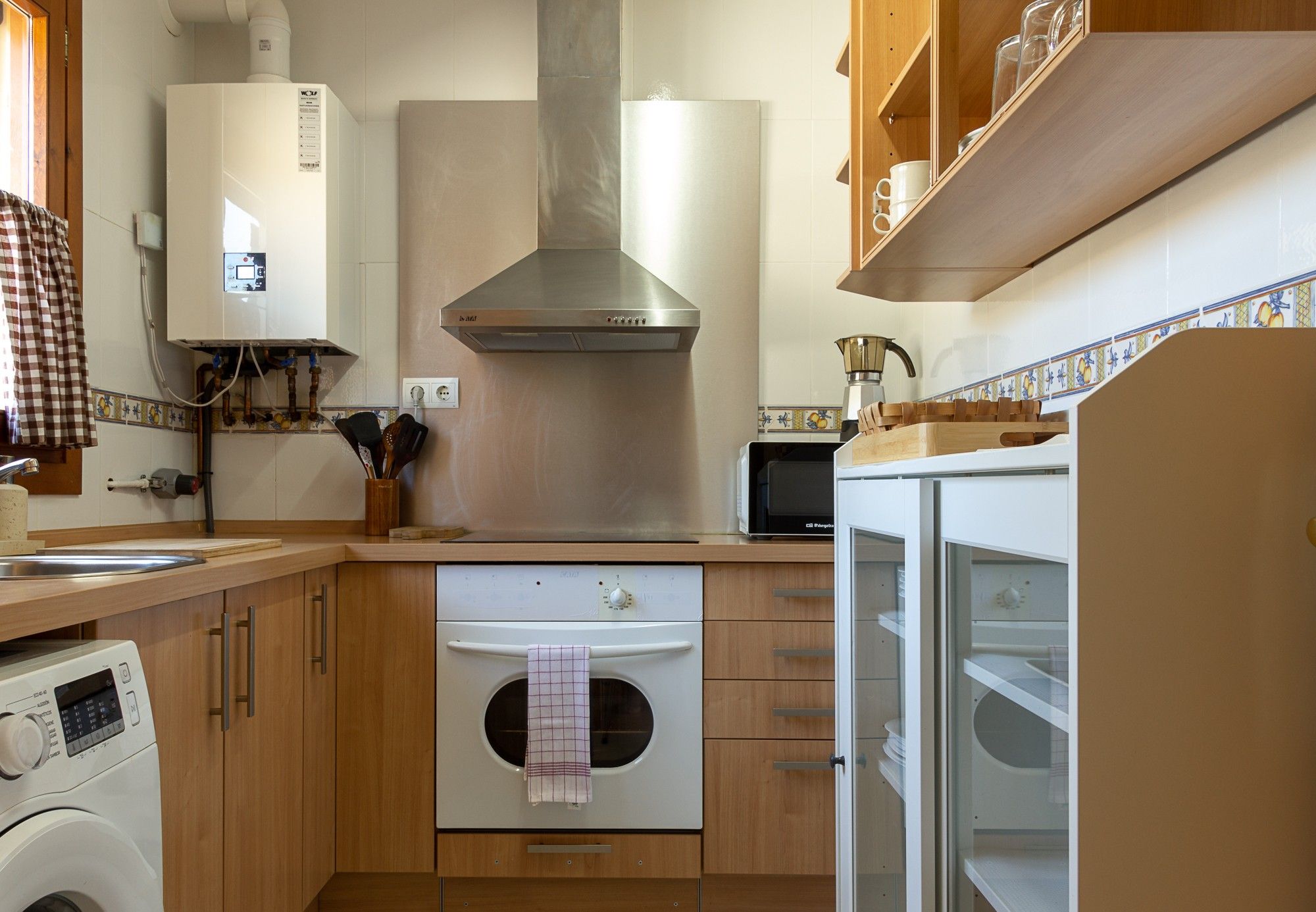 A kitchen with a built-in oven, microwave, and a stainless steel range hood.