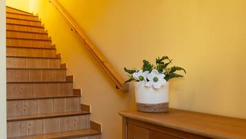 A wooden staircase with a basket of white flowers on a wooden bench.