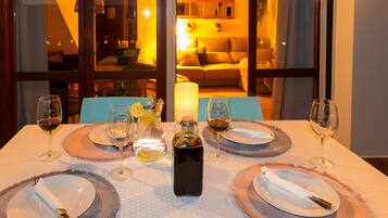 Una mesa de comedor lista para cuatro, con copas de vino, platos y una botella.