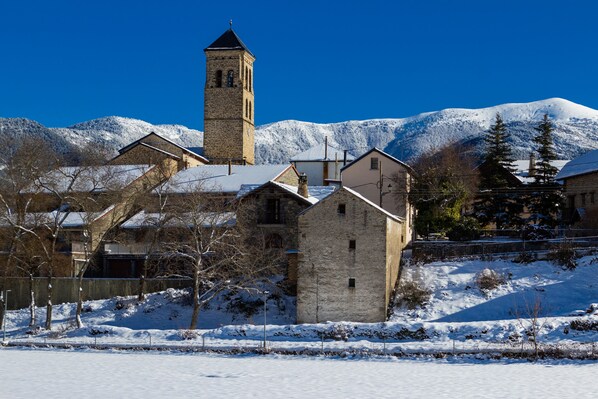 A snow-covered village with traditional stone buildings and a prominent church tower.