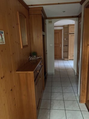 A wooden interior hallway with a welcome sign, a potted plant, and a tiled floor. - Alpenglühn Appartement/Fewo, Bad, WC, 3 Schlafräume by Interhome (Adelboden)