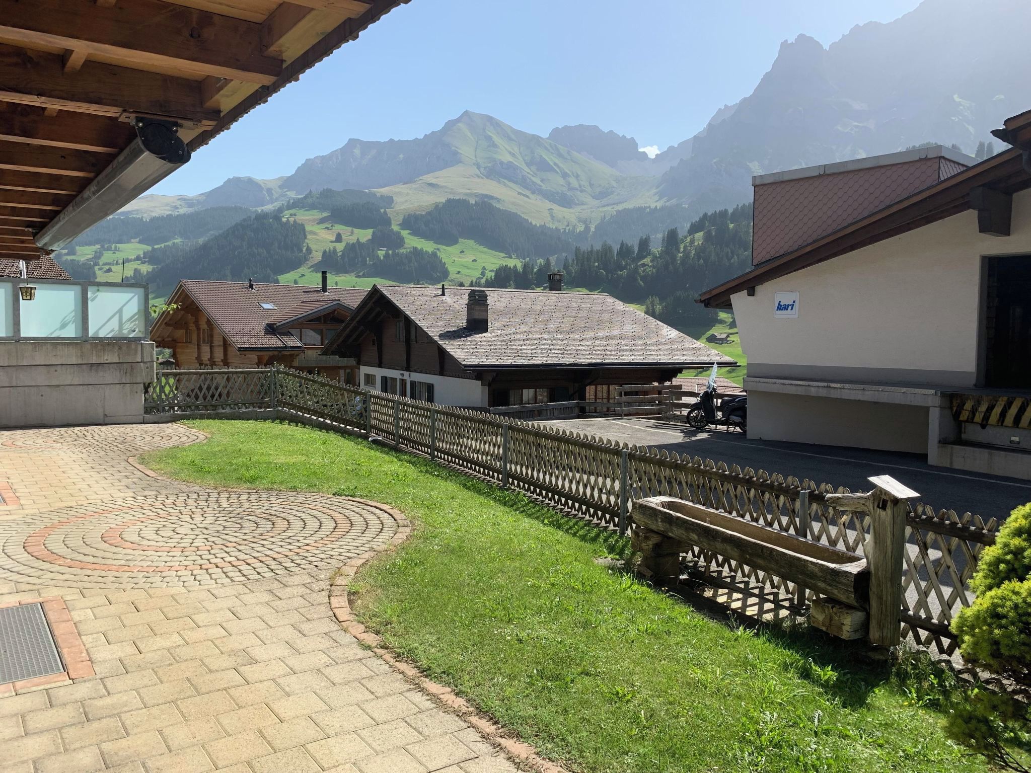 Ein Innenhof mit gepflastertem Weg, Holzzäunen und Gebäuden im traditionellen Baustil.