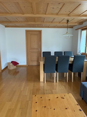 A dining area with a wooden table and chairs, a door, and a hanging light fixture. - Alpenglühn Appartement/Fewo, Bad, WC, 3 Schlafräume by Interhome (Adelboden)