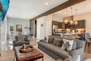 A spacious living area with a sofa, ottoman, and a dining table. - Luxury Grand Park Retreat with Private Hot Tub (Fraser)