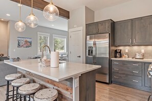 A modern kitchen with a central island, stainless steel appliances, and a view to the outdoors. - Luxury Grand Park Retreat with Private Hot Tub (Fraser)