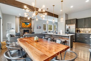 A modern kitchen with a central island, dark cabinetry, and a stainless steel refrigerator. - Luxury Grand Park Retreat with Private Hot Tub (Fraser)