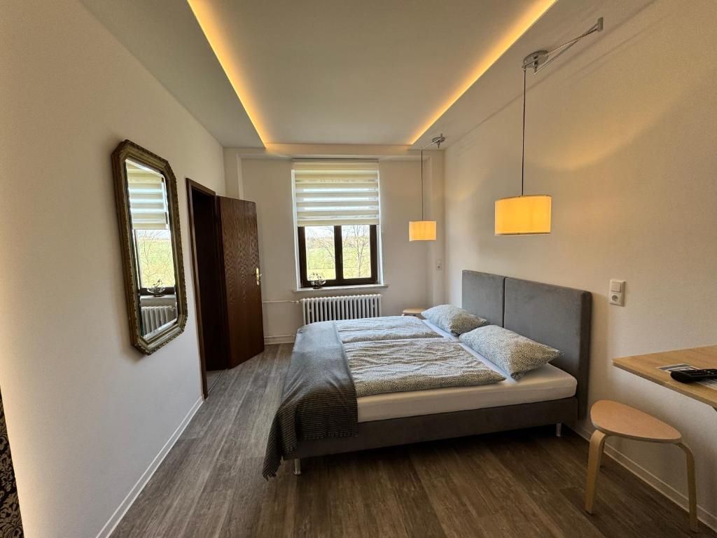 A bedroom with a bed, bedside table, lamp, and window with blinds.