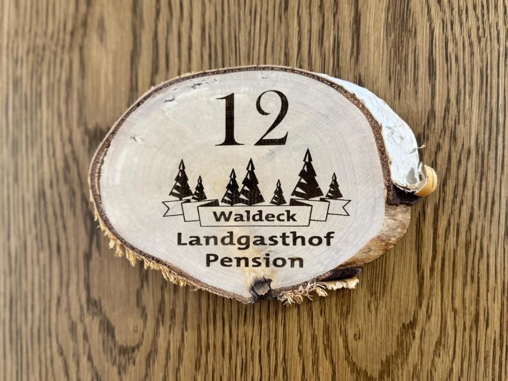 A wooden coaster with the number 12 and the text 'Waldeck Landgasthof Pension' on it.