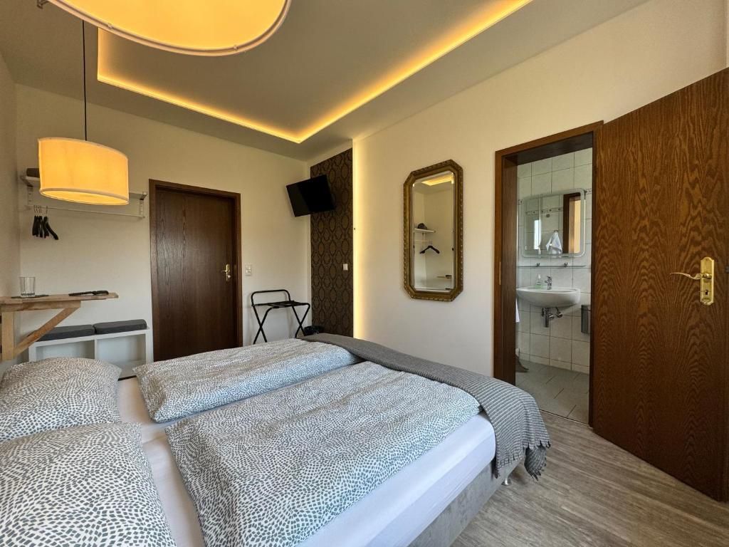 Ein Hotelzimmer mit einem Bett, einem Spiegel, einem Fernseher und einem durch eine offene Tür einsehbaren Badezimmer.