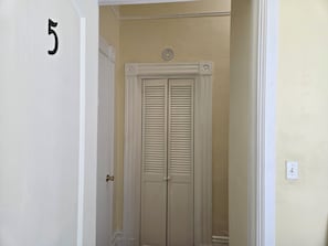 A closed door with a number '5' on the wall, a white door frame, and a light switch on the wall. - Sunny Two Bedroom in Uptown (Oakland)