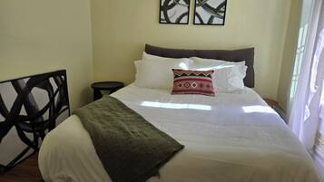 A bed with white bedding, a green throw blanket, and a decorative pillow. There are two wall-mounted artworks above the bed.