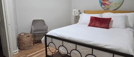 A bedroom with a bed, a chair, a lamp, and a wall art piece.