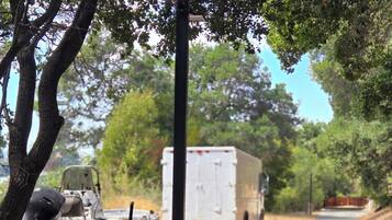 A paved road with a boat and a trailer on the left and a white truck on the right.