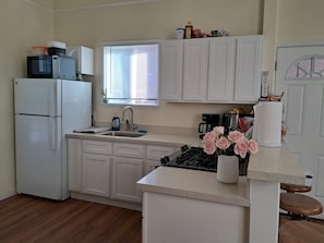 A kitchen with white cabinets, a refrigerator, a sink, a stove, and a window with blinds. - Sunny Two Bedroom in Uptown  (Oakland)
