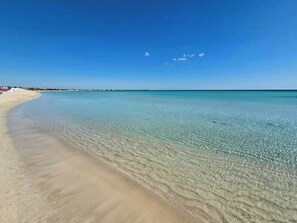 Ein Strand mit klarem, flachen Wasser und sandigem Ufer.