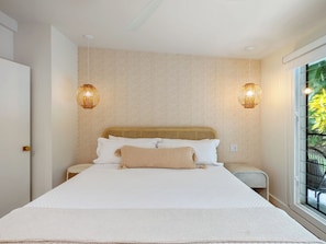 A bedroom with a large bed, two bedside lamps, and a window with a view of greenery. - Lanikai Monthly Home, Private Guest Suite, 2 Parking, and Walk to Beach (Kailua)