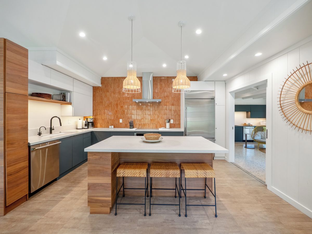 Una cocina moderna con una isla central, luces colgantes y una estufa empotrada.