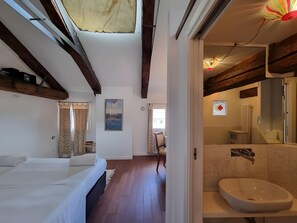 Quarto de hotel com cama, banheiro com pia e vista para o exterior.