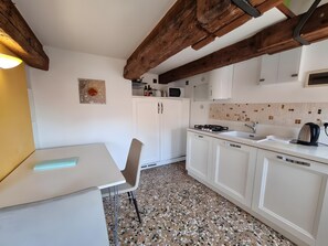 Eine Küche mit weißen Schränken, einer Granitabdeckung und einem Holzbalken an der Decke.