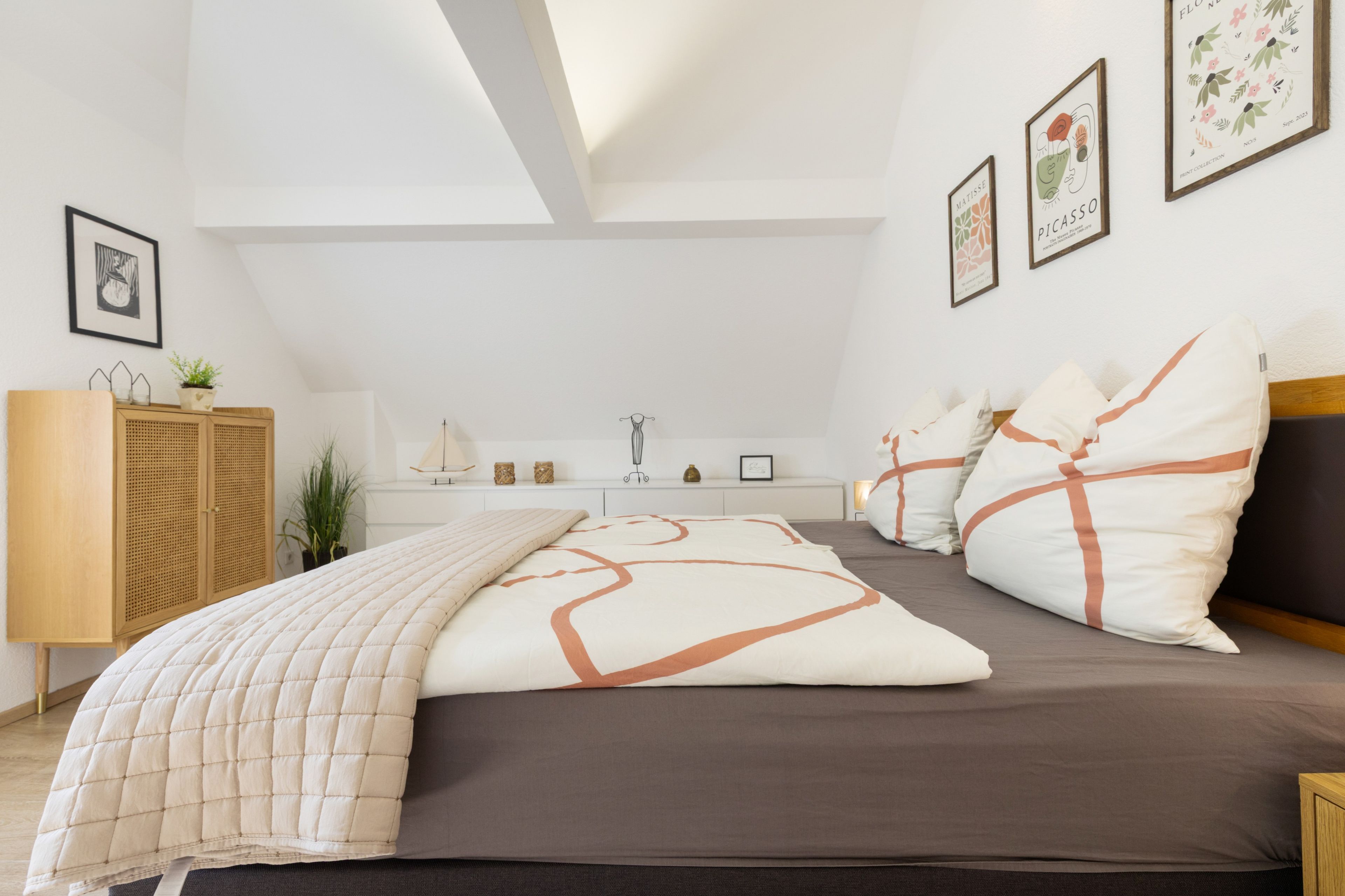 Un dormitorio con cama, mesitas de noche, armario y tragaluz.