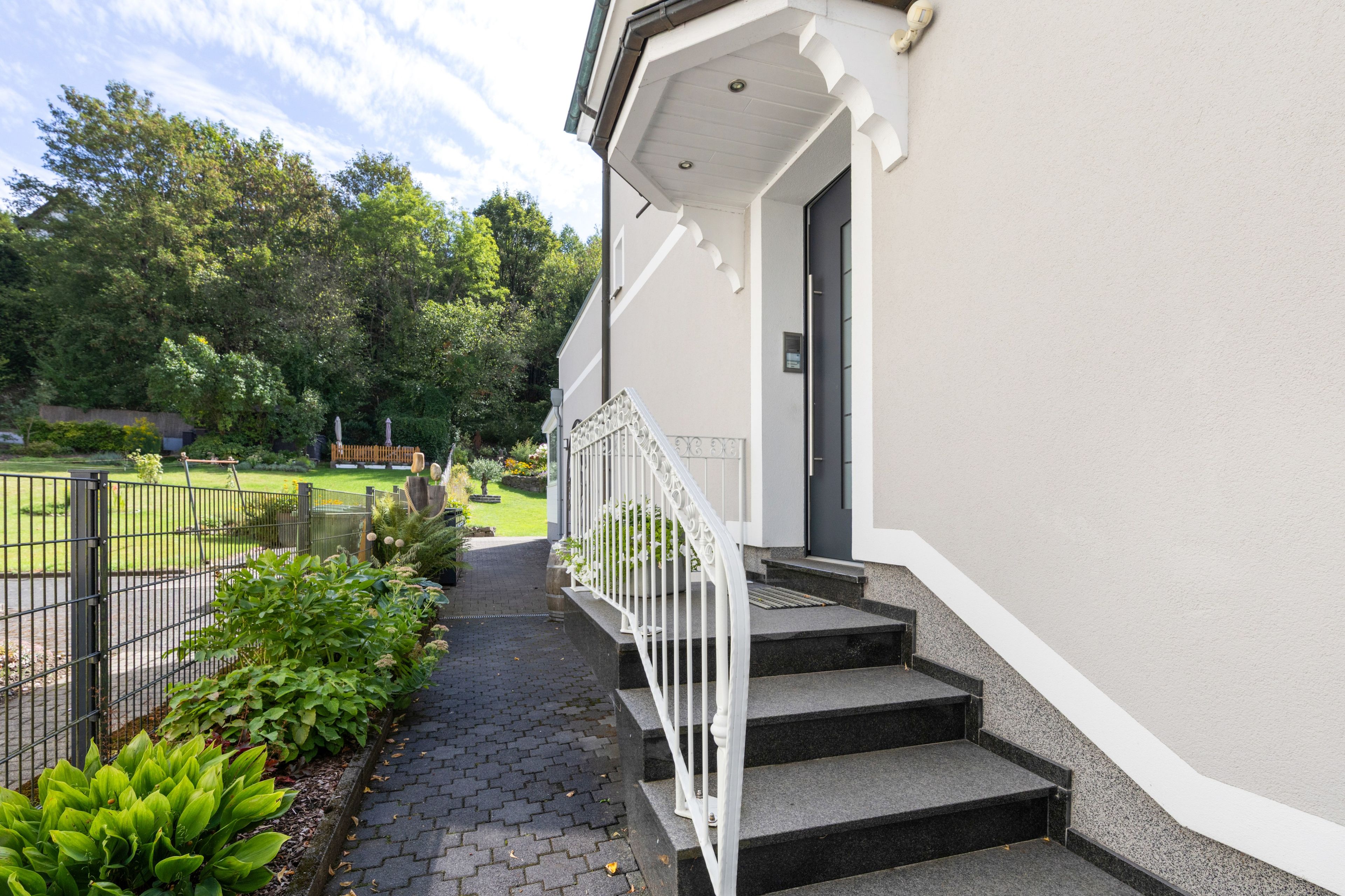 Ein Gebäude mit weißer Fassade, einer schwarzen Tür und einer weißen Treppe, die zum Eingang führt.
