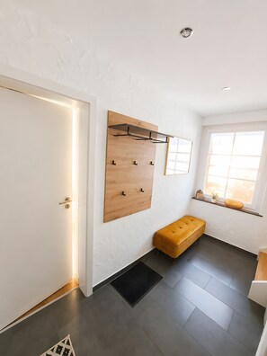 A room with a wooden wall-mounted rack, a bench, a door, and a window with a view. - Apartment “Welcome” with Private Rooftop Terrace (Olpe)