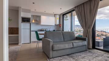 Een modern appartement met een grijze bank, een eethoek en een keuken.