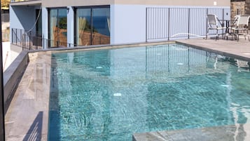 Una piscina limpia con borde de piedra, rodeada por un balcón con barandilla.