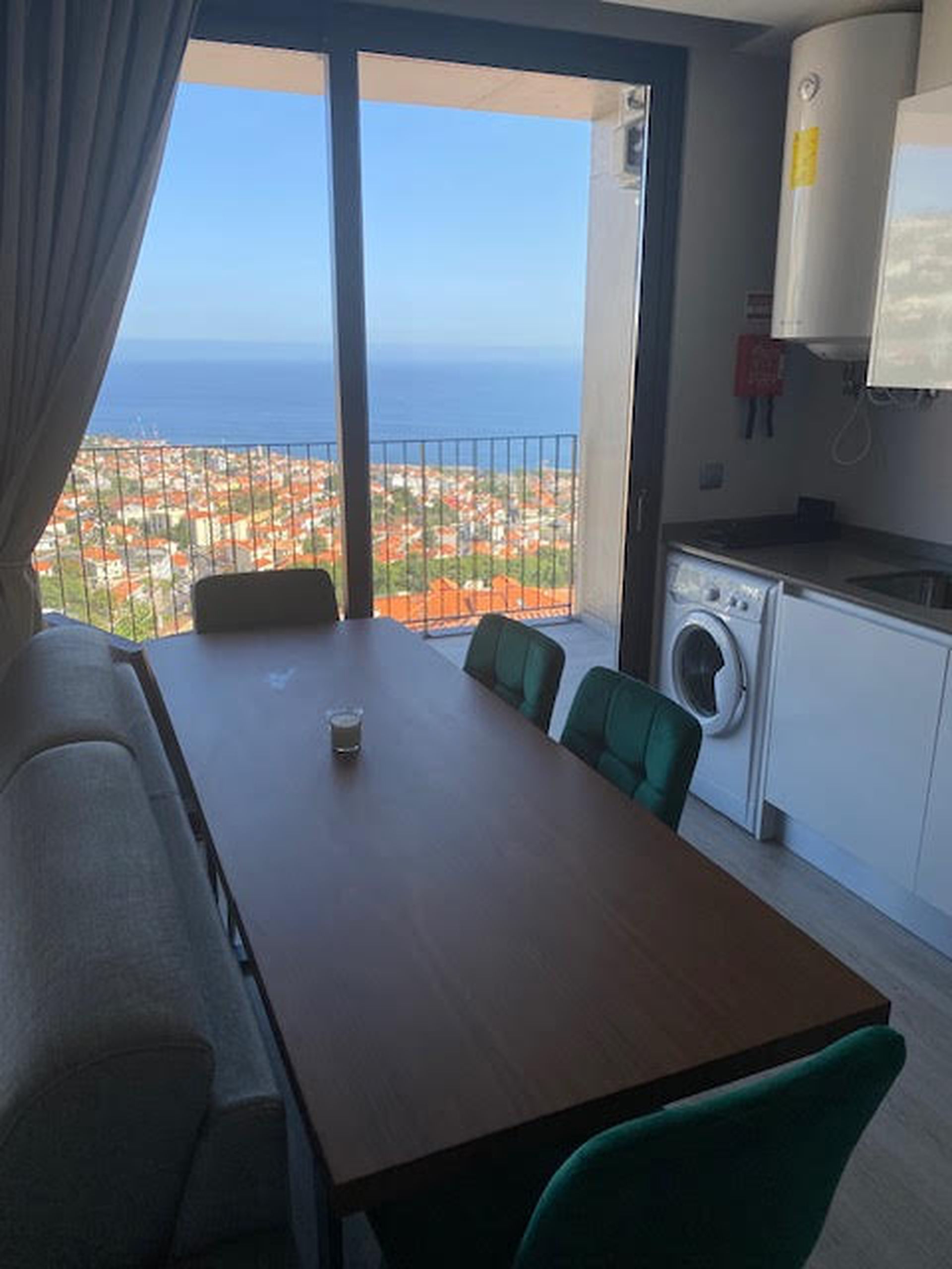 Una habitación con mesa de comedor, sillas, lavadora y vistas al mar y al paisaje urbano.