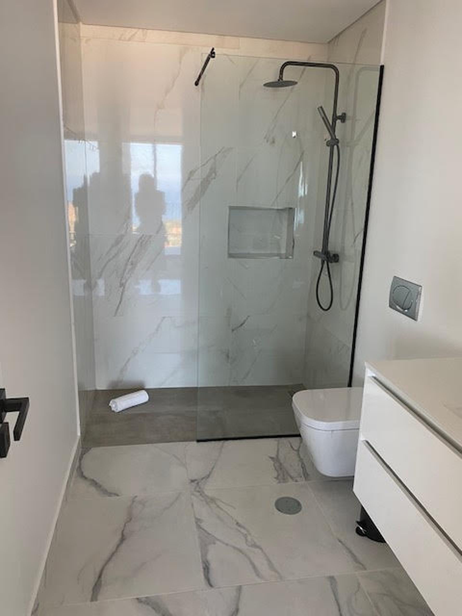 Une salle de bain moderne avec une douche à parois de verre, des toilettes et un meuble-lavabo avec un miroir.