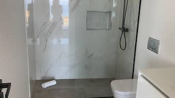 Une salle de bain moderne avec une douche à parois de verre, des toilettes et un meuble-lavabo avec un miroir.