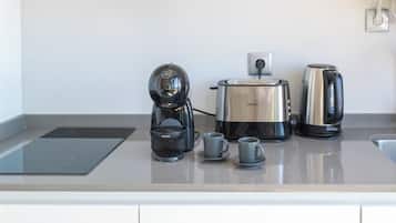 A kitchen with a coffee maker, a kettle, and two cups on the counter.