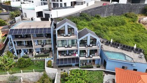 Um hotel com vários andares, varandas, piscina e painéis solares.