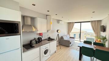 A modern kitchen with a washing machine, a dining area with a table and chairs, and a sofa.