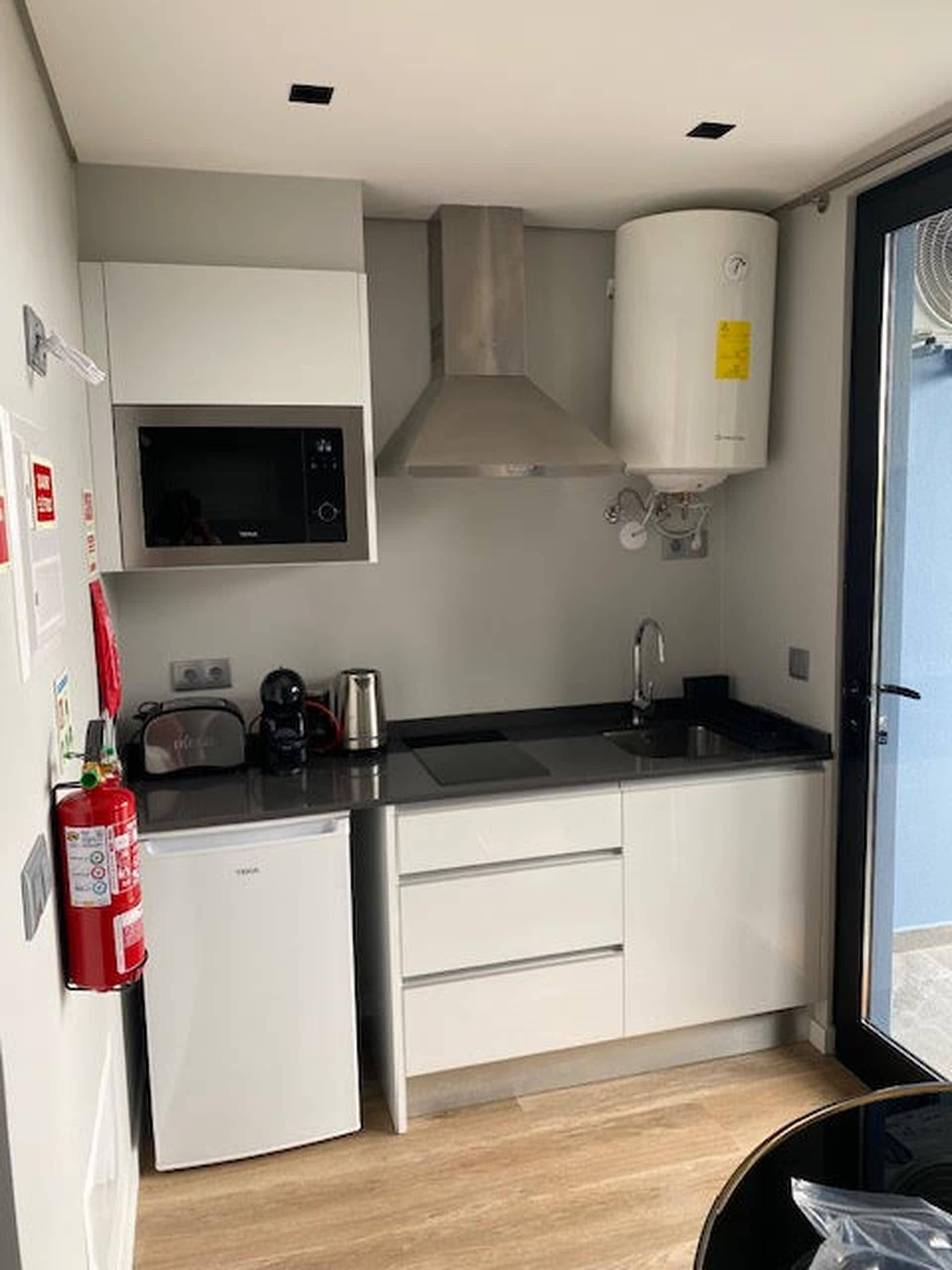 A compact kitchen with a microwave, stove, and a small refrigerator.