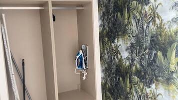A room with a wardrobe, a mop, and a vacuum cleaner.