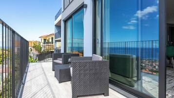 Un balcon aménagé avec du mobilier d’extérieur et une porte vitrée donnant sur une terrasse.