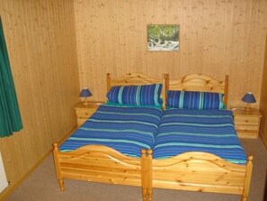 Ein Doppelbett mit Holzrahmen und zwei Nachttischen, jeweils mit einer Lampe.