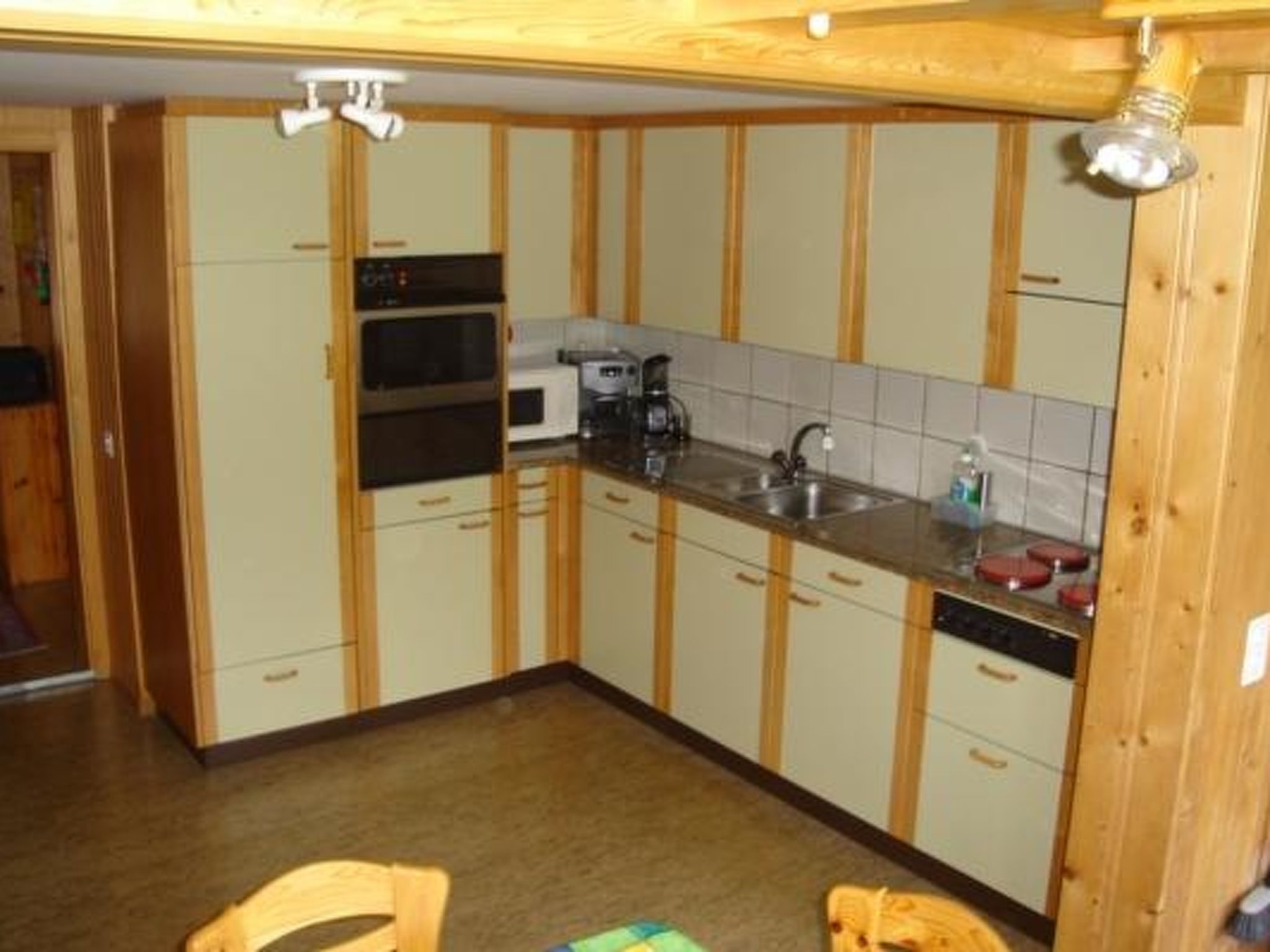 Eine kleine Küche mit Holzausstattung, einer Mikrowelle, einer Kaffeemaschine und einem Spülbecken.